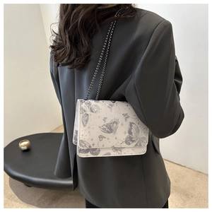 Detail of the cream chain crossbody bag with butterfly patterns on a PU leather flap