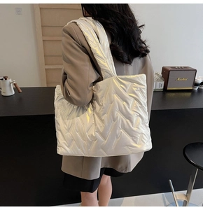 Silver quilted tote bag in glossy finish shown from a side-view on a model's shoulder