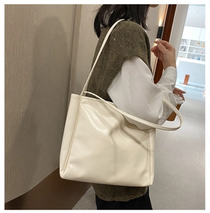 Minimalist beige leather tote bag with natural texture shown in a casual lifestyle scene