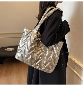 Side view of a large metallic champagne gold quilted tote bag worn with a black wool coat