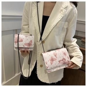 Vue détaillée du sac bandoulière blanc et à main avec imprimé papillon rose et chaîne métal
