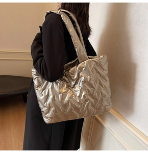 Side view of large silver quilted tote bag with padded straps on model in a modern room