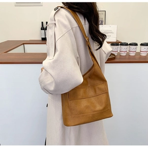 Hobo style caramel shoulder bag with magnetic flap pocket shown in a cafe setting