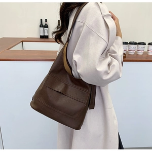 Model wearing dark brown vintage tote bag in a minimalist cafe setting for daily commuting