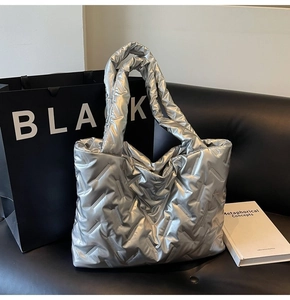 Detailed view of silver quilted tote bag with metallic finish on black leather sofa