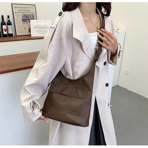 Macro shot of dark brown pebbled leather shoulder bag with flap pocket and metal buckle