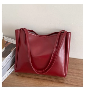 Close-up of deep red leather tote bag with fine stitching details on wooden desk