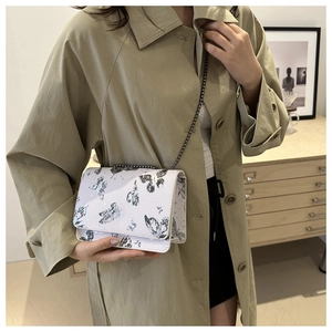 Détail du petit sac blanc à imprimé papillon noir et bandoulière en chaîne métal