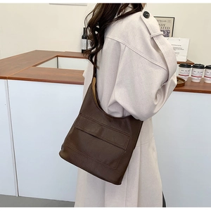 Close-up of a brown lychee pattern leather hobo bag styled with a minimalist beige trench coat