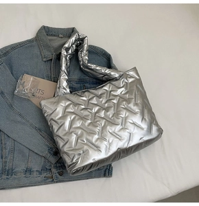 Detail of silver puffy tote bag with herringbone stitching on denim jacket background