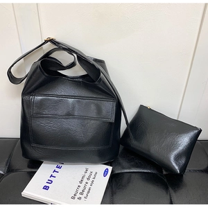 Detail of black tote bag set including matching zipper pouch with textured leather