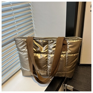 Detailaufnahme der gesteppten Metallic-Tasche mit breiten braunen Web-Schultergurten