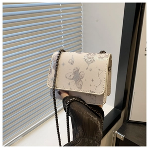 Détail d'un sac bandoulière crème avec imprimés papillons et bandoulière en chaîne
