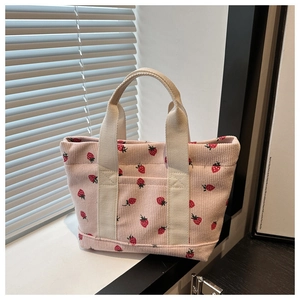 Detail of pink corduroy tote bag with strawberry prints and white canvas handles