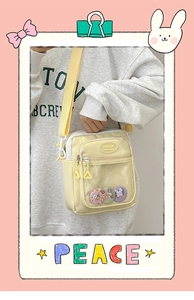 Detail view of a beige crossbody bag with transparent pocket and cute rabbit badges