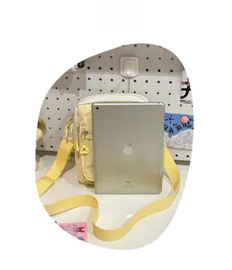 Mini yellow canvas crossbody bag size comparison with an iPad showing compact storage