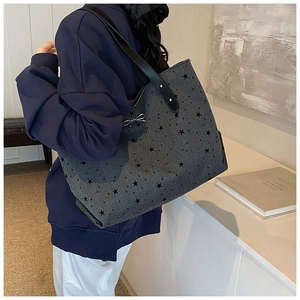 Detalle de bolso tote gris con estrellas negras y lazo plateado en la correa para el hombro