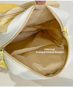 Detail view of the interior compartment and yellow dual zippers of this beige crossbody bag