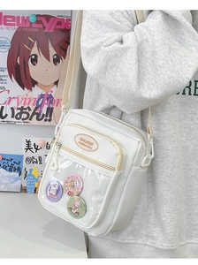 Close-up of white crossbody bag with clear PVC pocket and cute cartoon bunny badges