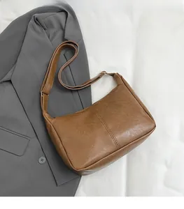 Detail einer braunen Kunstledertasche mit Faltenstruktur und goldener Schnalle
