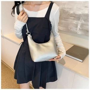 Bolso de hombro plateado en forma de media luna con textura de lichi usado por modelo