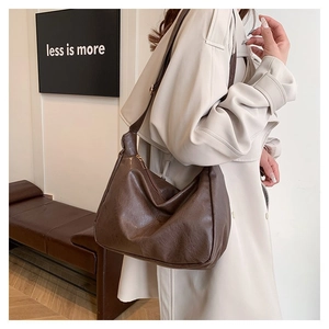 Detailansicht große braune Schultertasche mit weicher Textur und breitem Gurt am Modell