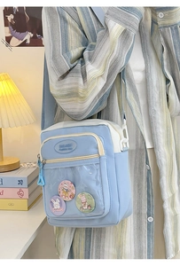 Detail of light blue crossbody ita bag with clear PVC window and cute bunny badges