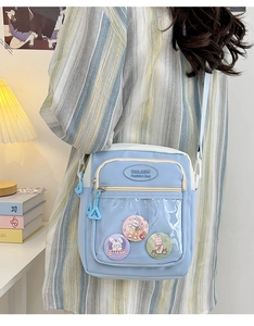 Detail of light blue ita bag showing transparent window with cute cartoon badges
