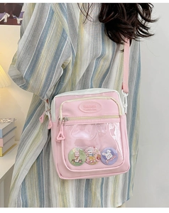 Pink and white ita bag with clear window and rabbit badges shown worn by a model