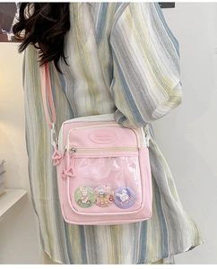 Detail of pink ita bag with transparent window featuring cute cartoon rabbit badges