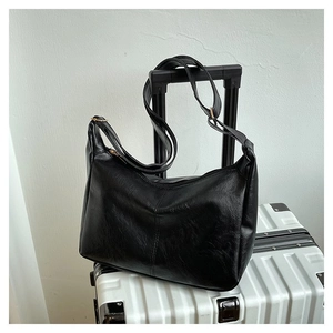 Detail einer schwarzen Hobo-Tasche aus Leder mit verstellbarem Riemen auf Koffer
