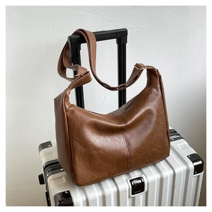 Detailansicht braune PU-Leder Umhängetasche mit Vintage-Textur auf weißem Koffer