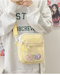 Detail of yellow canvas ita bag featuring a transparent PVC front pocket and badges