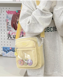 Detail of clear PVC pocket on yellow crossbody bag with cute rabbit badges and zipper layers