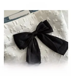 Detail of black satin bow decoration on white star embossed fabric for tote bag