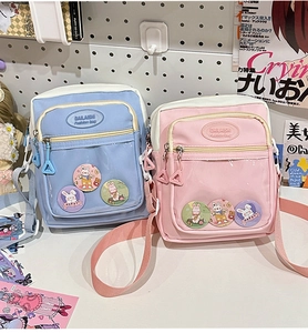 Detail of transparent PVC window on candy-colored messenger bags with cute bunny badges