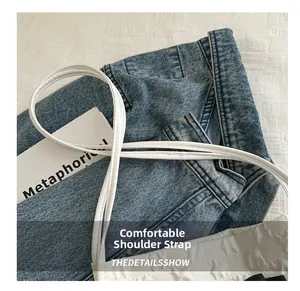 Detail of blue denim tote bag showing contrast white shoulder strap and fine stitching