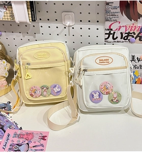 Detail view of cream and white Ita bags with clear PVC pockets and cute bunny badges