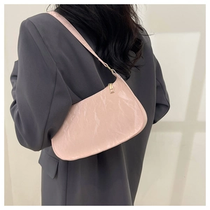 Dettaglio della borsa sottobraccio rosa plissettata con texture lucida su blazer