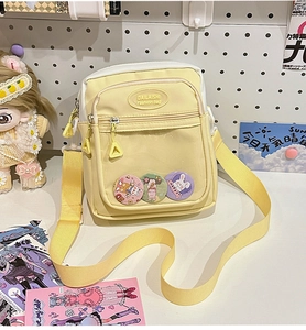 Detail of yellow itabag with transparent PVC window and three cute cartoon badges