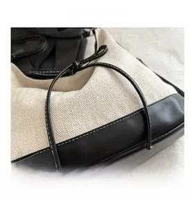 Detail of cream herringbone canvas and black leather stitching with white contrast seams