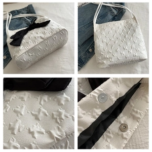 Detail view of jacquard fabric texture and black bow on white tote bag with magnetic snap