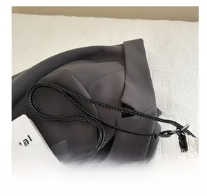 Close-up of black leather strap with white stitching on beige canvas tote bag