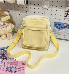 Detail of light yellow canvas crossbody bag with clear window and adjustable strap