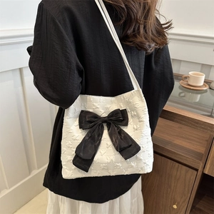 Close-up of elegant white tote bag with a large black bow and 3D textured fabric