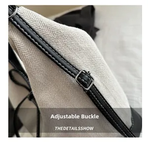 Detail of herringbone fabric tote with black leather strap and silver metal buckle