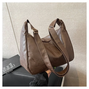 Detail der dunkelbraunen Hobo-Tasche aus Kunstleder mit Retro-Faltenstruktur und Trägern