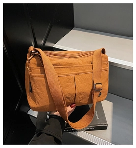Détail du sac bandoulière en nylon orange caramel avec plusieurs poches zippées