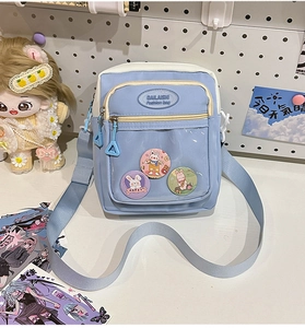 Detail of blue ita bag with transparent window, cute badges and adjustable strap