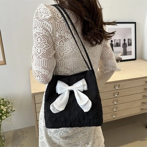 Detail of black tote bag with white bow and star texture worn over the shoulder